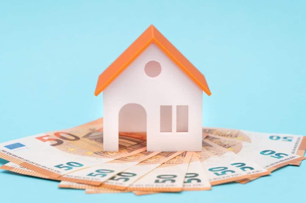 white toy house and euros on a blue background with free space for tex