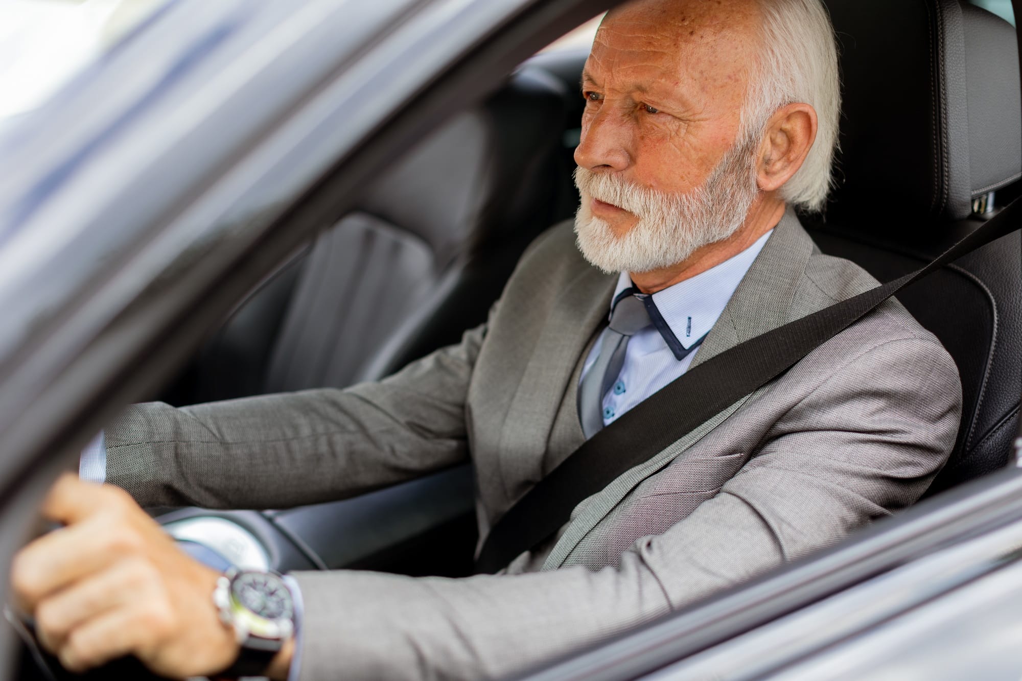 Joyful senior gentleman enjoying a leisurely drive in his modern car on a sunny day