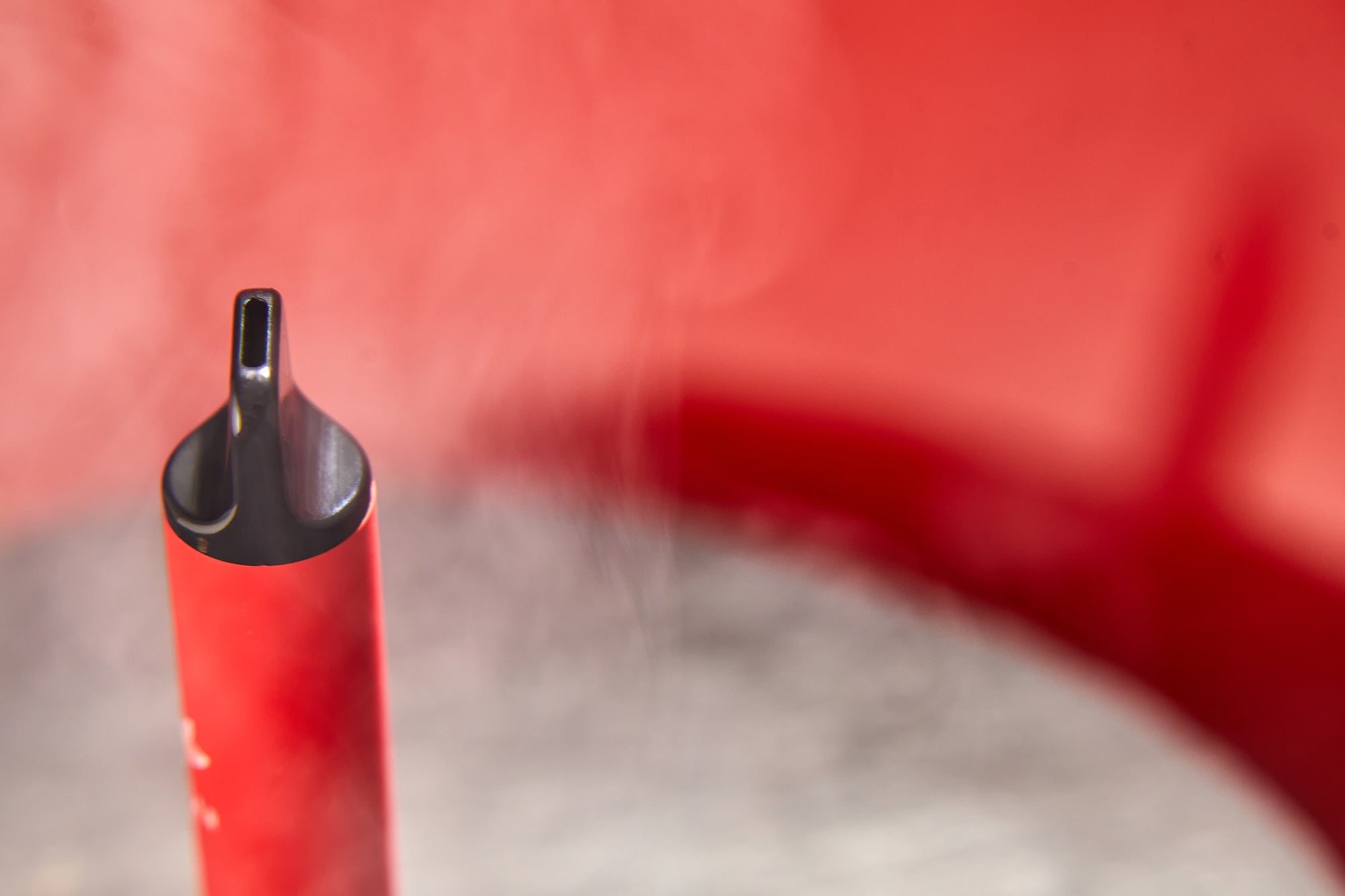 One disposable red e-cigarettes, and vapes in with smoke.